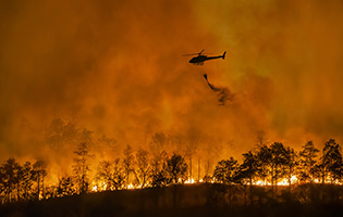 helicopter spraying water on california wildfire